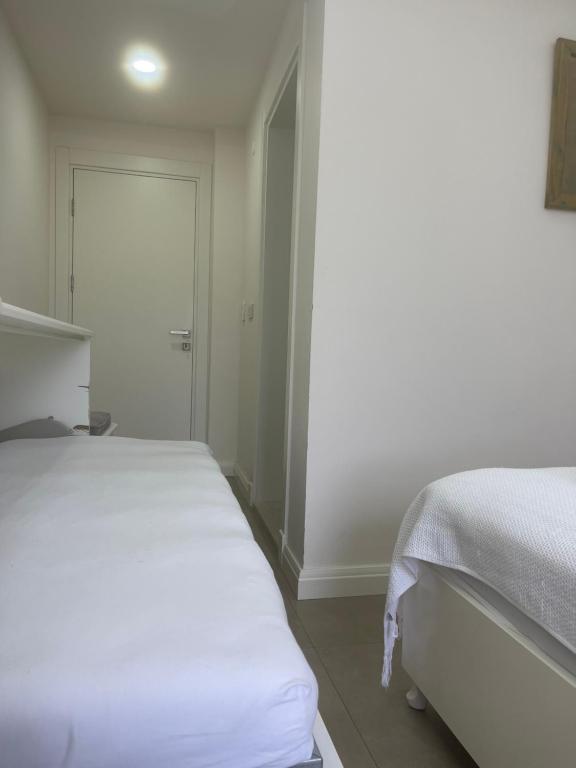 a white bedroom with two beds and a door at Dalyan Risus Suite in Çeşme