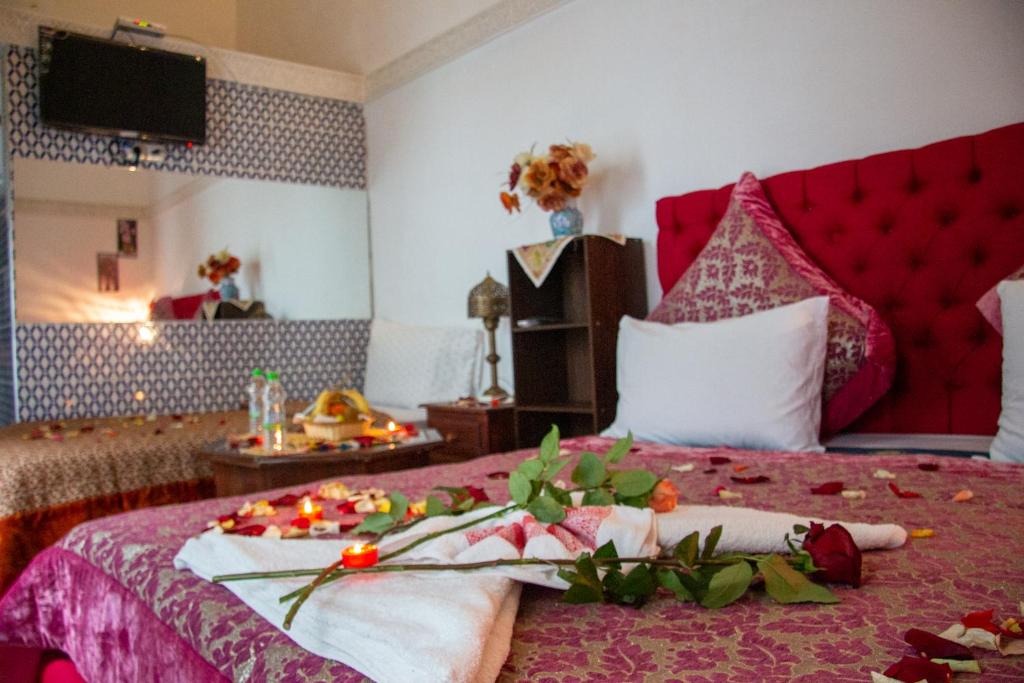 a bedroom with a red bed with flowers and candles on it at Riad Baba in Fez
