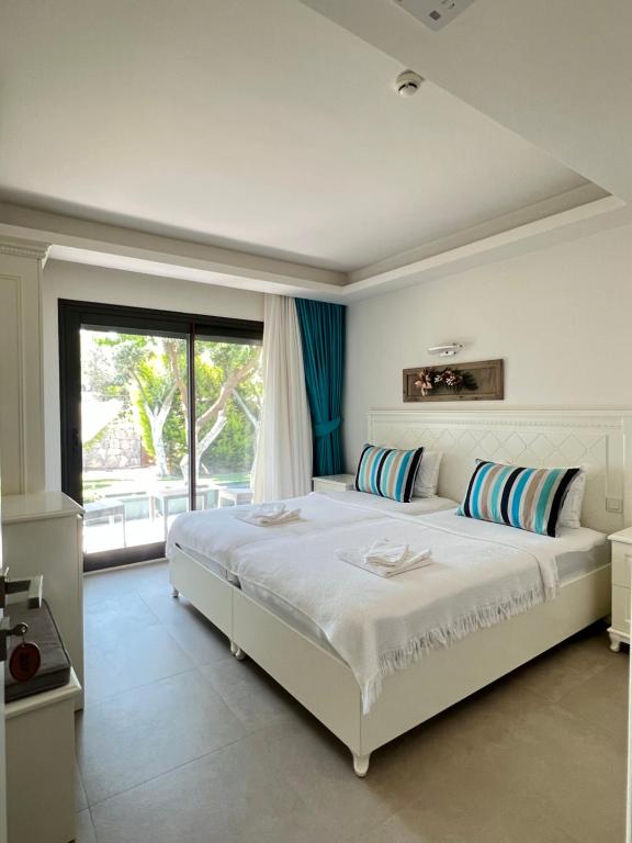 sypialnia z dużym białym łóżkiem i oknem w obiekcie Dalyan Risus Suite w mieście Çeşme