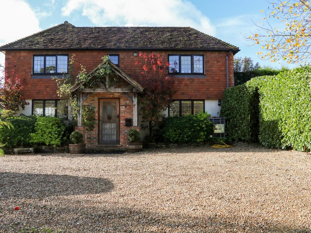 a brick house with a gravel driveway at 1 Northside Cottages in Godalming