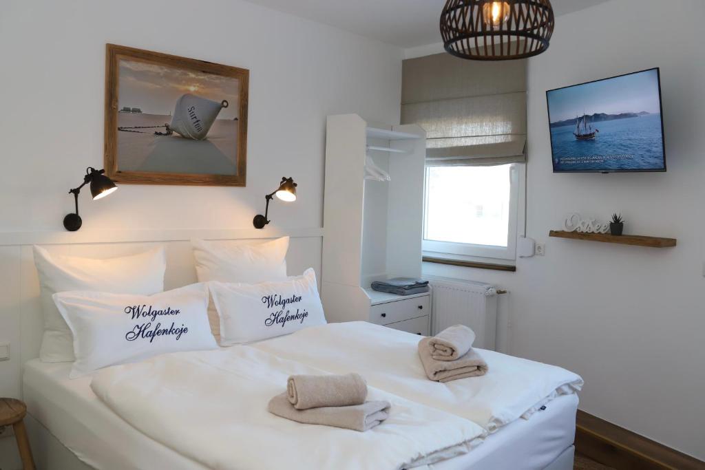 Un dormitorio con una cama blanca con toallas. en Hafenkoje Zum Anker en Wolgast
