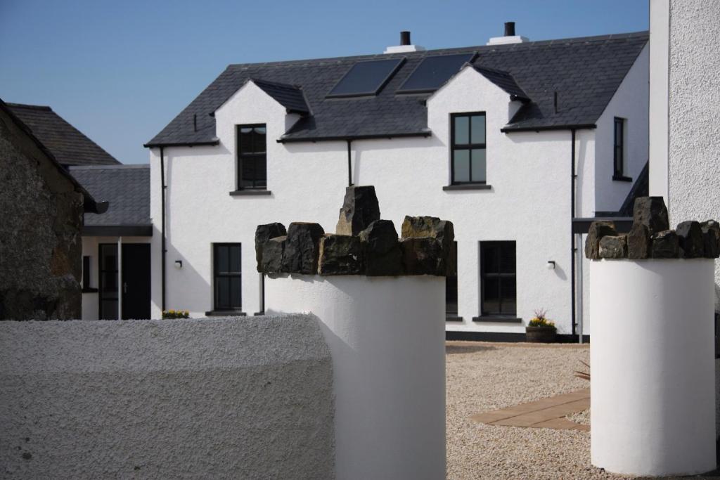 Casa blanca con paneles solares en el techo en Bayview Farm Holiday Cottages, en Bushmills