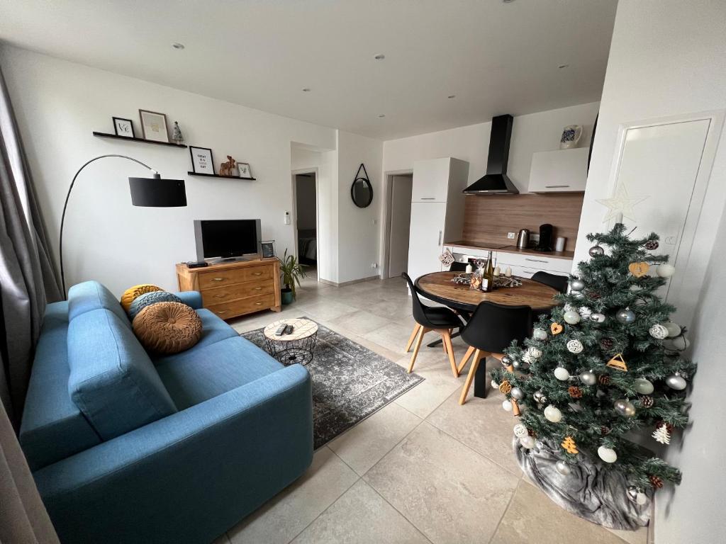 un salon avec un canapé bleu et un arbre de Noël dans l'établissement Appartement plain-pied au coeur de l'Alsace, à Muttersholtz