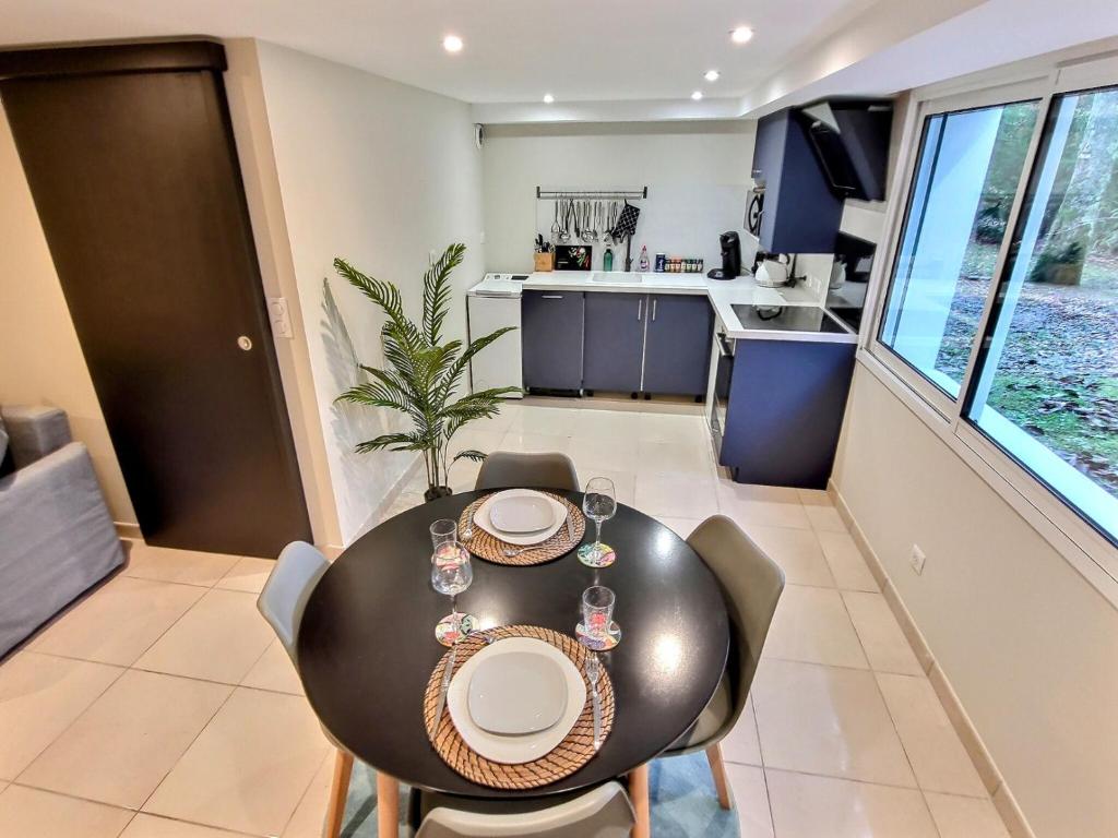 une salle à manger avec une table et des chaises noires dans l'établissement Le Petit Rocher 30m2- Studio standing 3 étoiles, à Saint-Aignan-Grand-Lieu