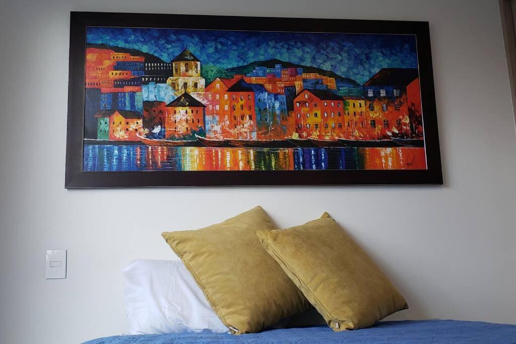 una pintura en una pared sobre una cama en Robles10 El Cable Luxury Highrise, en Manizales