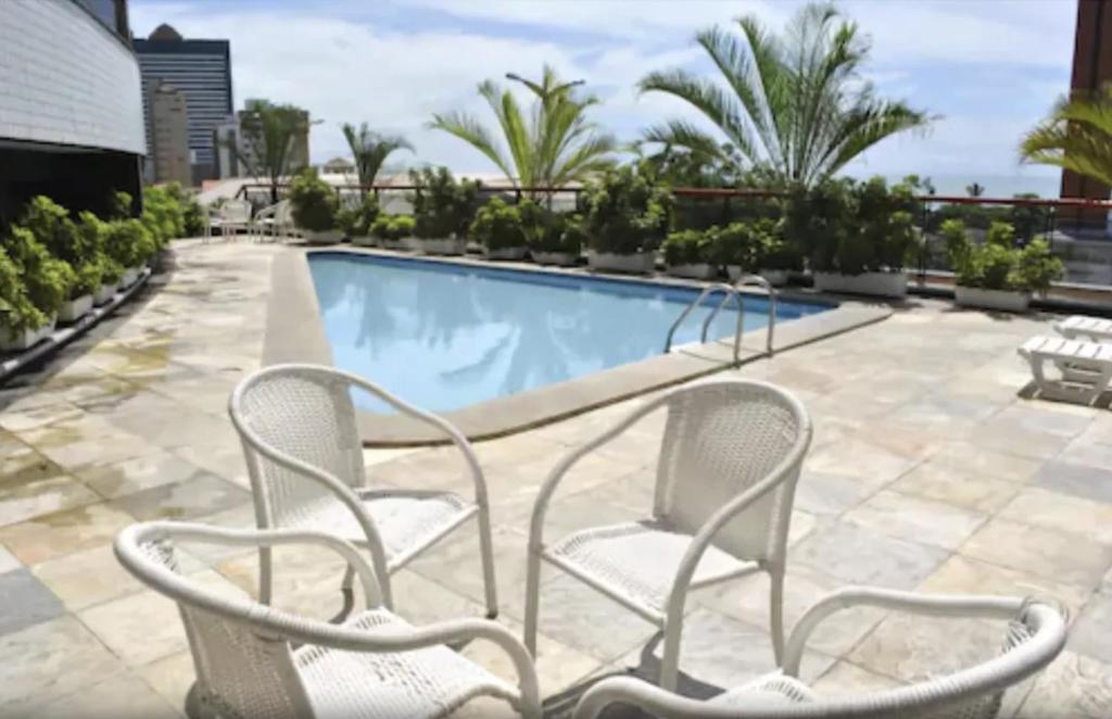 una piscina con 2 sillas blancas al lado en Hotel Ocean View Residence, en Fortaleza