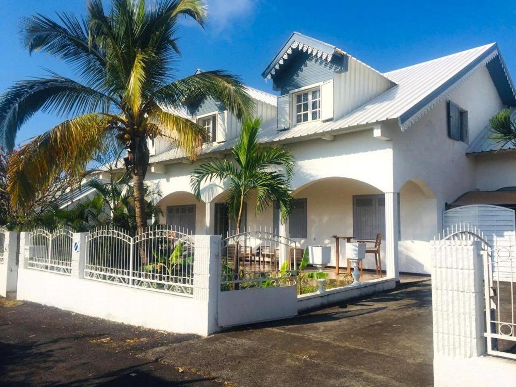 une maison blanche avec des palmiers devant elle dans l'établissement Le Caillou Blanc, à Saint-Paul