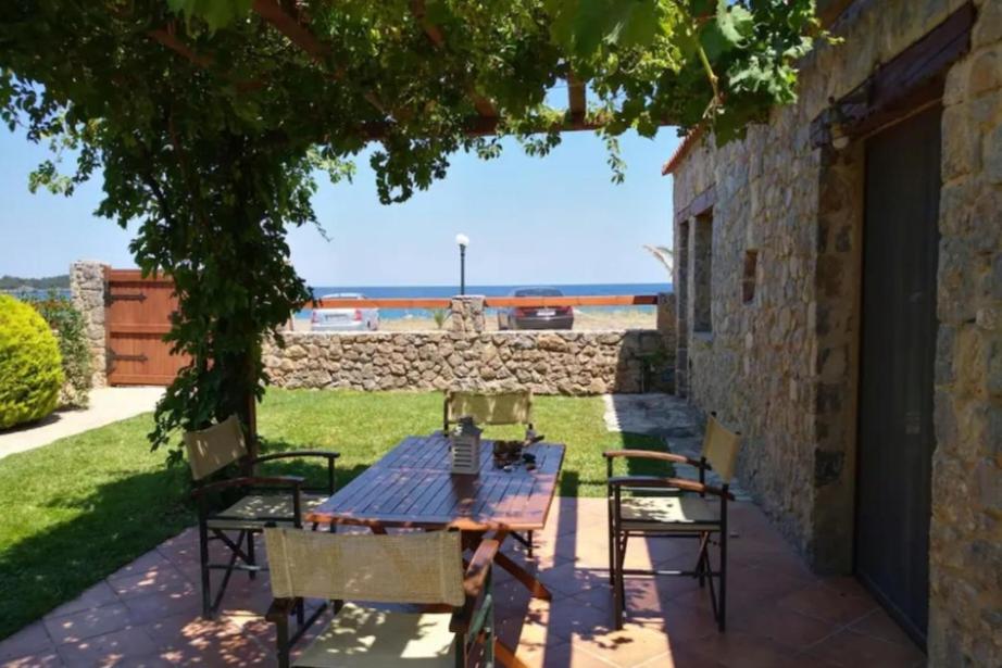 a table and chairs on a patio with a view of the ocean at Villa Agali. in Agia Anna