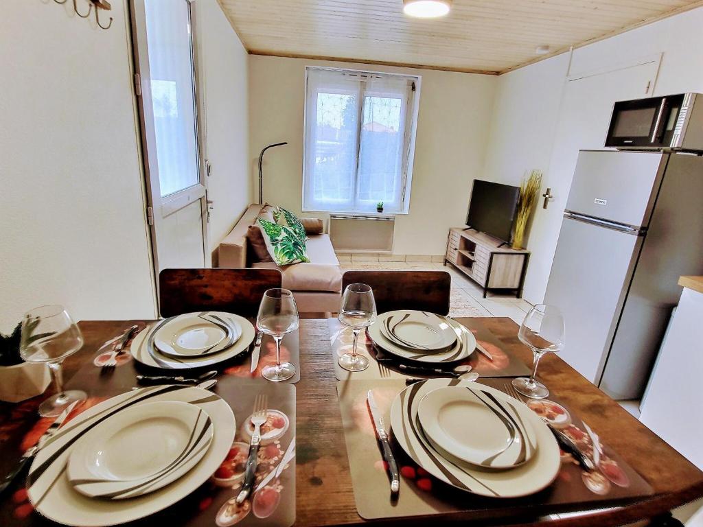 a dining room table with plates and wine glasses on it at Into the Wild - T2 Cosy tout confort in Bouguenais