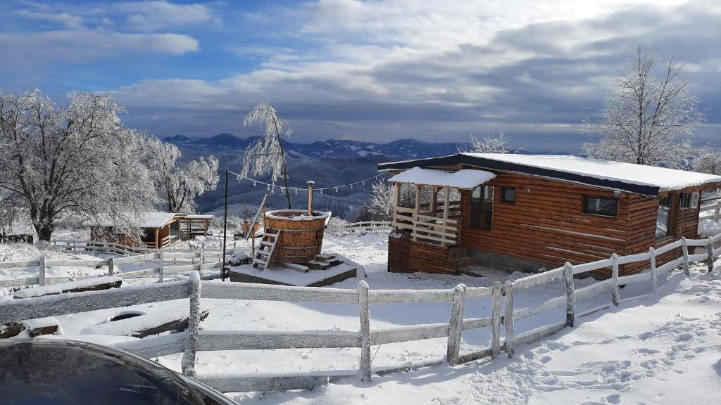 a wooden cabin in the snow with a fence at Cabana Himalaya Lodge cu ciubăr din inima munților Apuseni- masivul Buces -Vulcan 