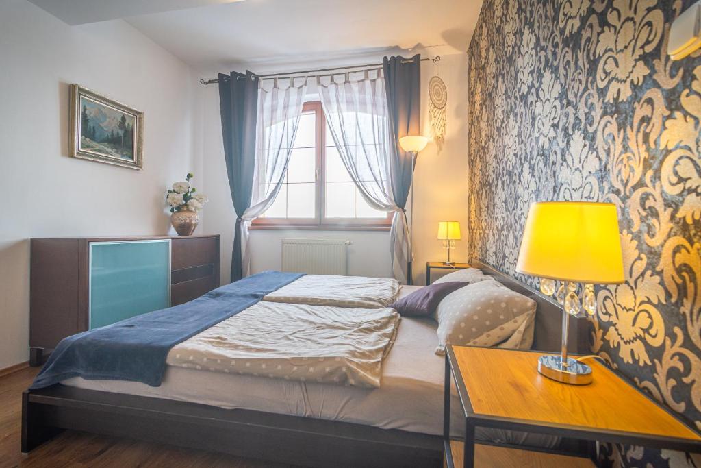 ein Schlafzimmer mit einem Bett und einem Tisch mit einer Lampe in der Unterkunft TATRYSTAY Great Apartment - 2 King size beds in Veľká Lomnica