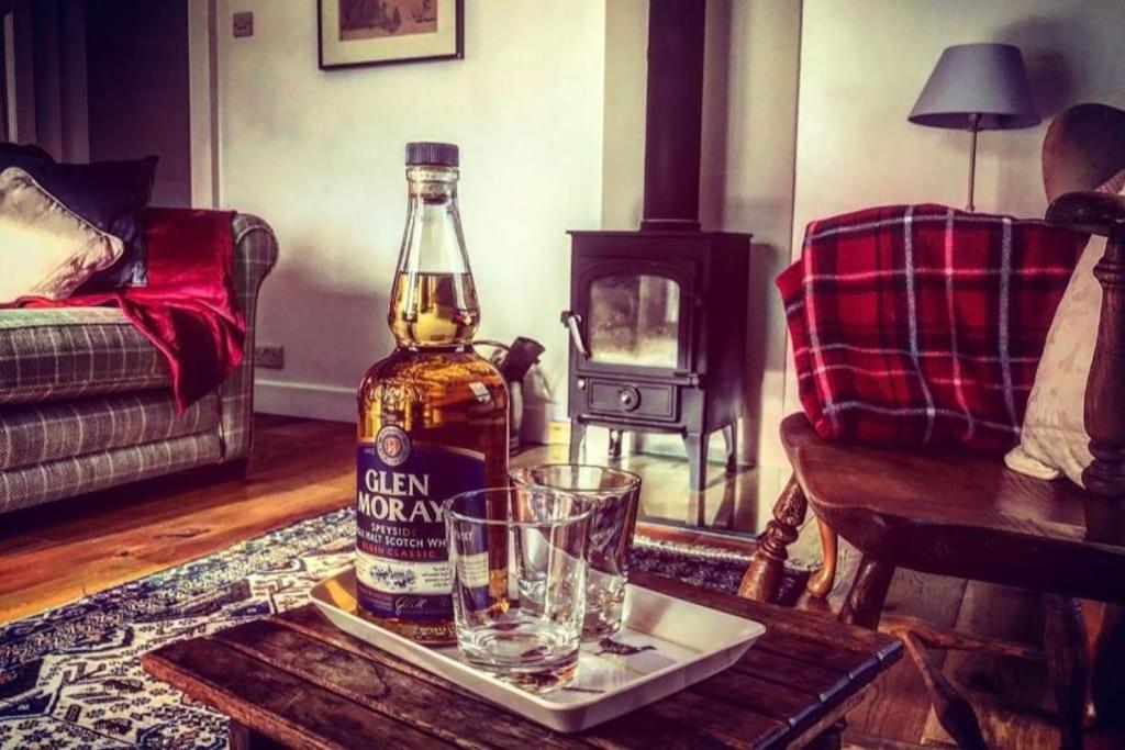 a bottle of alcohol and glasses on a table in a living room at Folly View - Private, peaceful apartment with stunning views. in Pateley Bridge