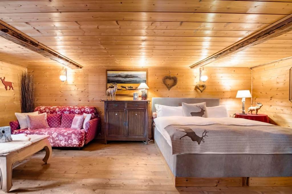 um quarto com uma cama grande e um sofá em "CHALET dei FIORI" room & apartment em Bedretto
