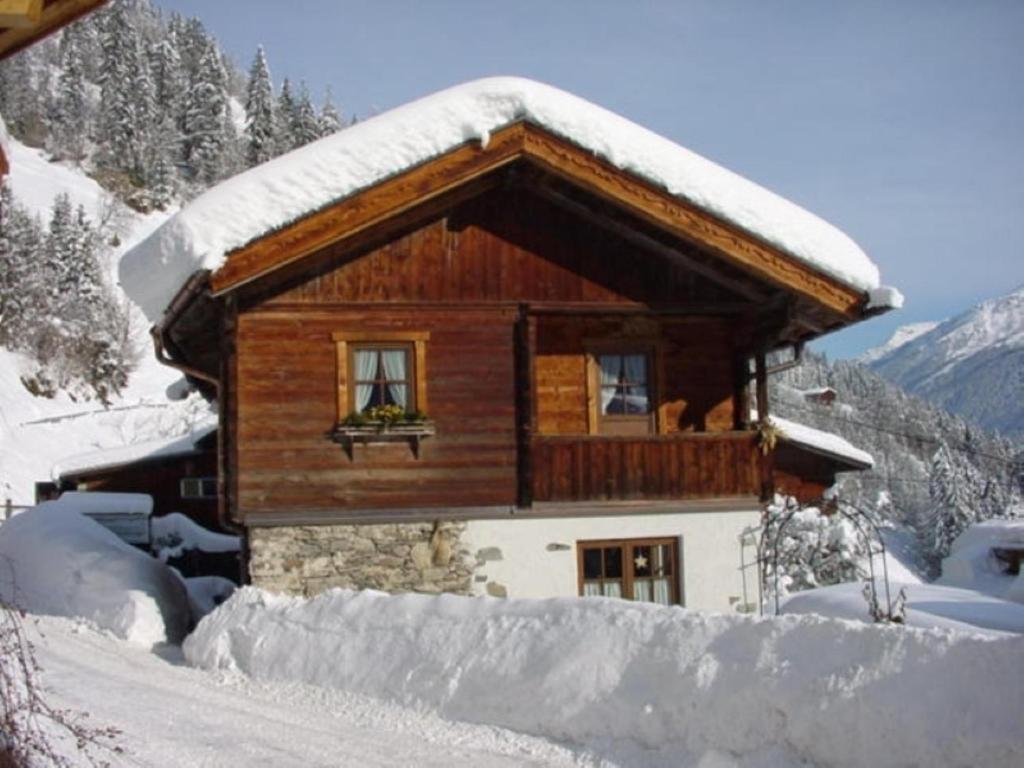 Cabaña de madera con nieve en el techo en Waschhütte, Ferienhaus, en Finkenberg