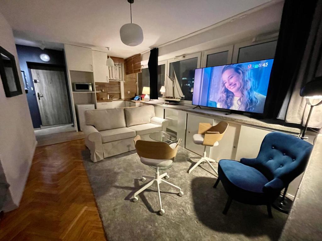 a living room with a couch and a tv and chairs at Super GREY 2 metro fast WiFi 65’TV Netflix HBO AppleTV+ in Warsaw