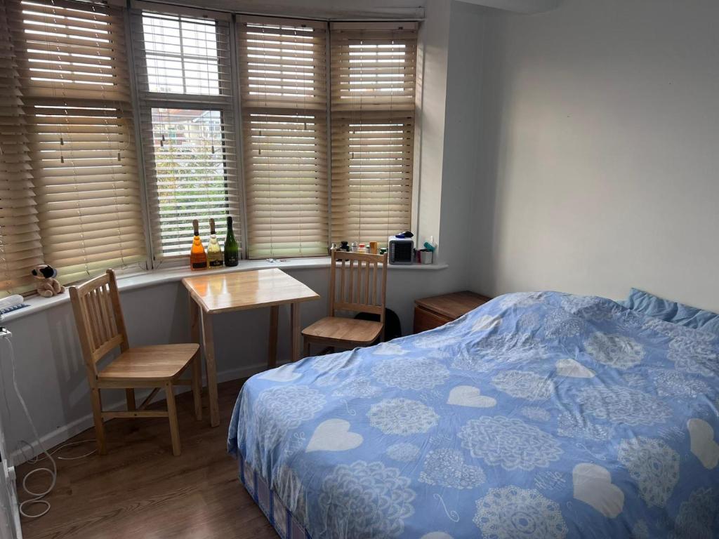 1 dormitorio con 1 cama, mesa y sillas en HEART OF HANGER LANE, en Londres