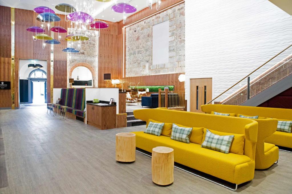 Sandman Signature Aberdeen Hotel & Spa في أبردين: لوبى به أريكة صفراء وكراسي خشبية