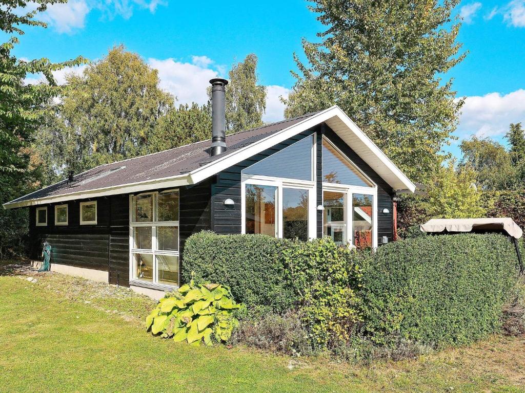 una casa negra con una ventana y algunos arbustos en Holiday home Præstø V en Præstø