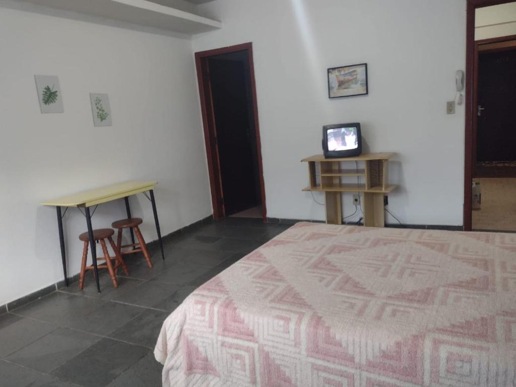 ein Schlafzimmer mit einem Bett, einem Tisch und einem Stuhl in der Unterkunft Kit ótima localização - Águas de Lindoia in Águas de Lindóia