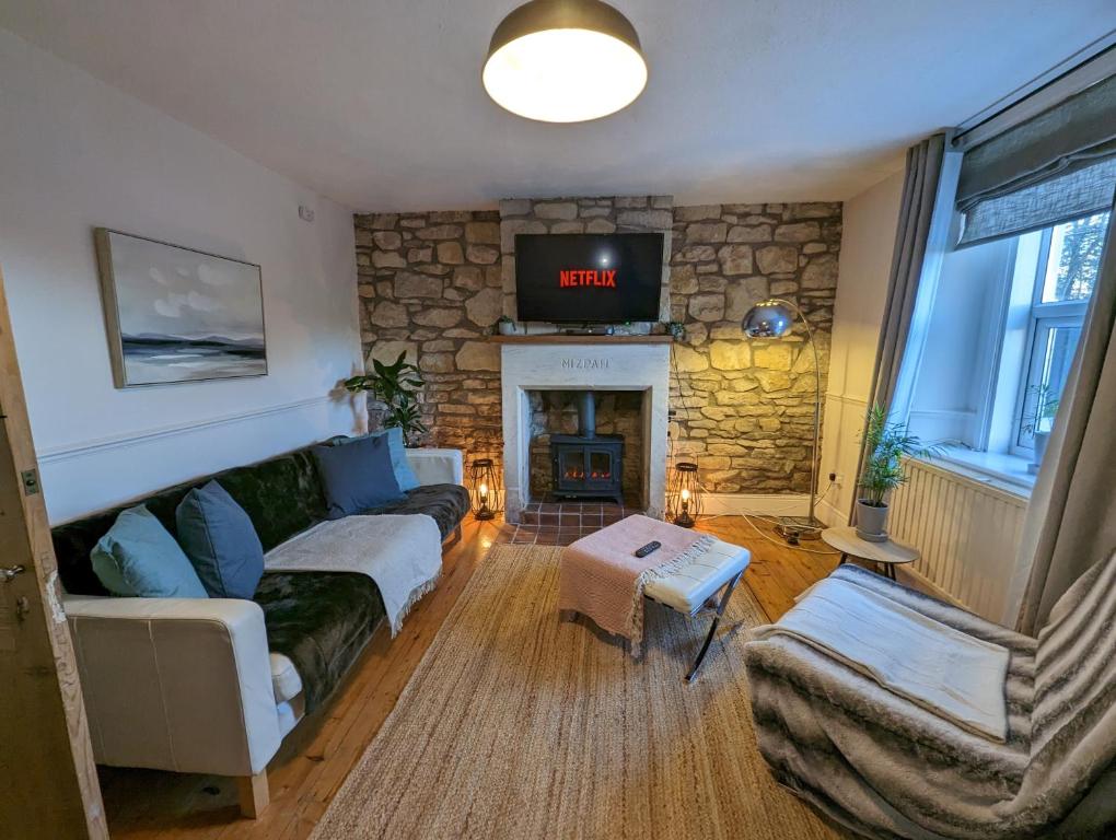 a living room with a couch and a stone fireplace at Rush Hill Cottage - with parking for 2 cars in Bath