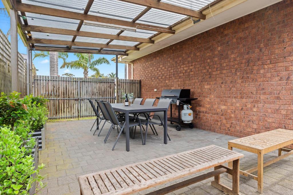 a patio with a table and chairs and a brick wall at Skip, Shop, Splash in Rye