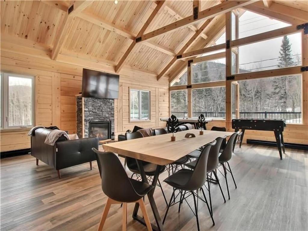 a dining room with a table and chairs and a fireplace at Chalet l'amical avec Spa in Saint-Philémon