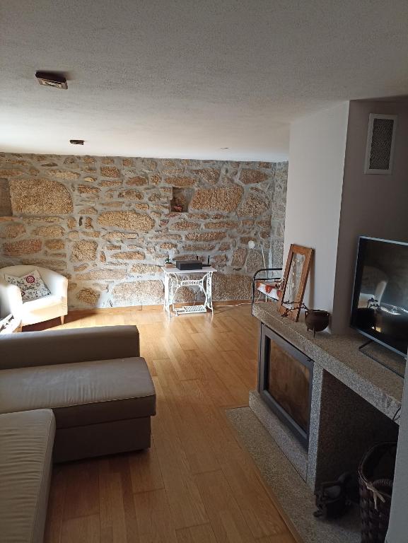 a living room with a couch and a stone wall at Casa do Soito. in Avelãs de Ambom