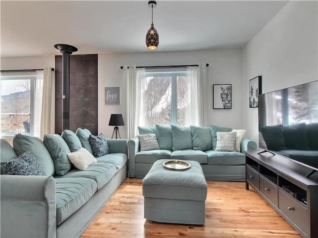 ein Wohnzimmer mit einem blauen Sofa und einem Tisch in der Unterkunft LE FÉÉRIQUE- CHALET AVEC SPA in Saint-Philémon