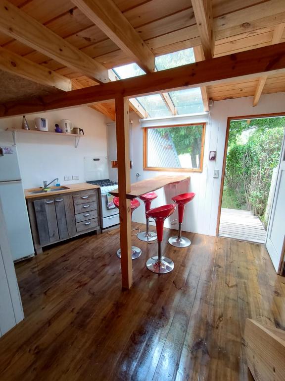 una cocina con taburetes rojos en una casa pequeña en Hermosa cabaña en la entrada de San martín de Los Andes en San Martín de los Andes