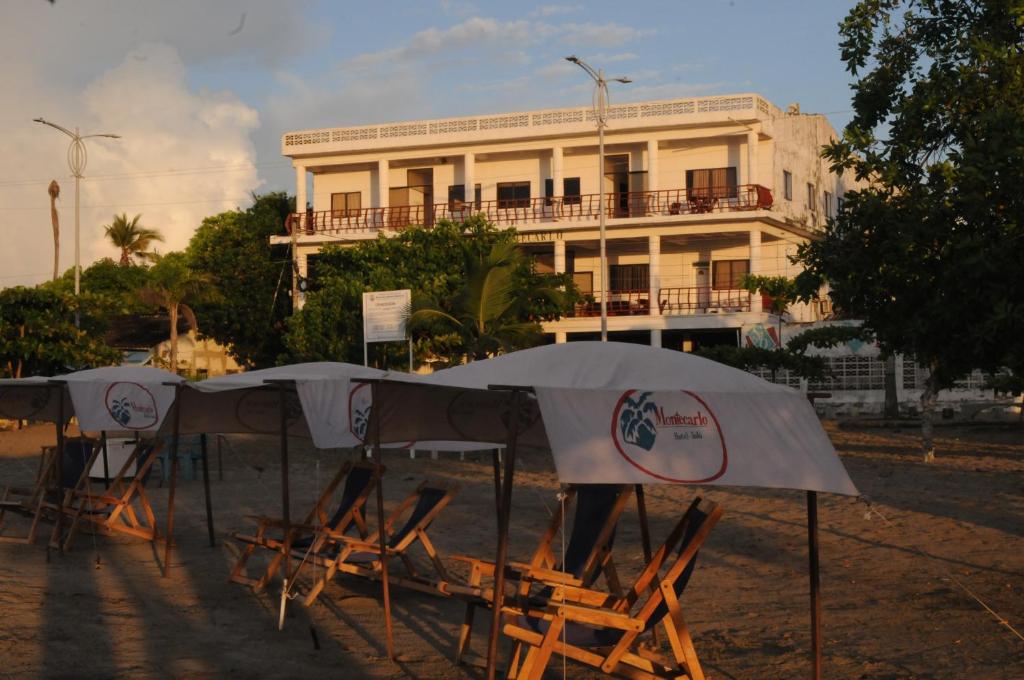 托盧的住宿－Hotel Montecarlo Beach，一组椅子和遮阳伞在建筑前