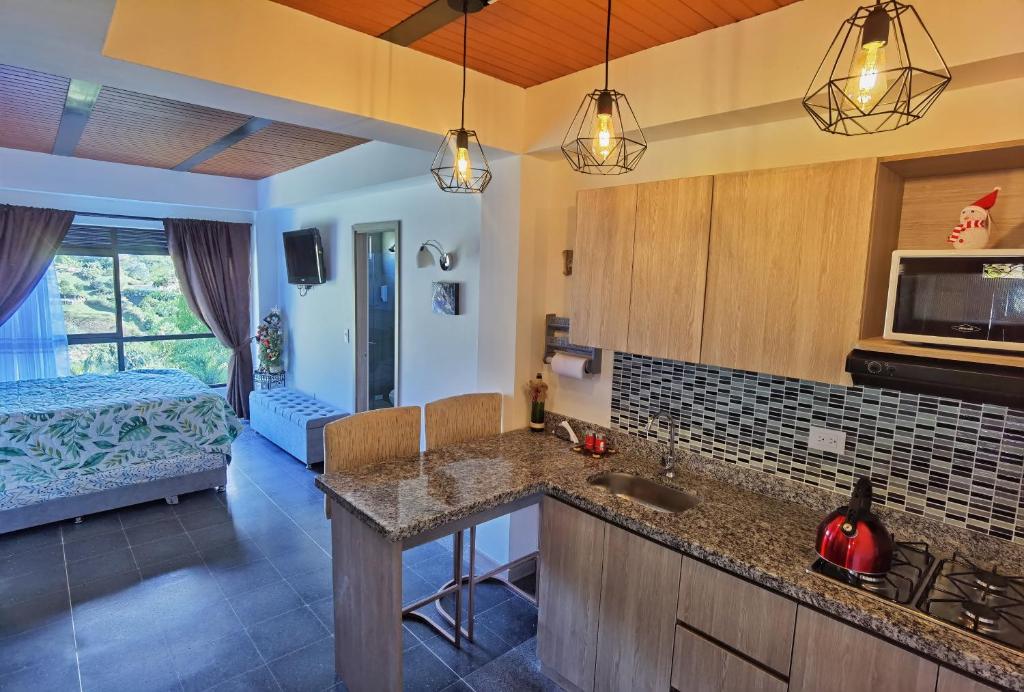 a kitchen with a counter top and a room with a bed at Descanso Bajo La Piedra Del Peñol in Guatapé