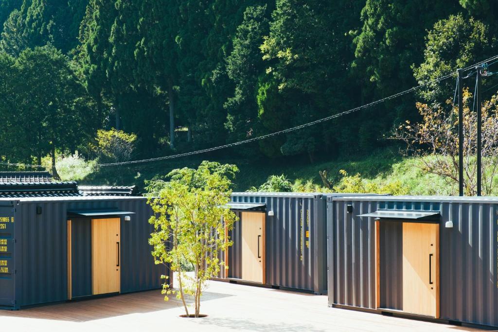 a row of grey storage buildings with orange doors at 安全第一 客室　コンテナハウス in Nishiawakura