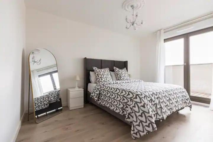Schlafzimmer mit einem schwarzen und weißen Bett und einem Spiegel in der Unterkunft Paris & Chill in Rosny-sous-Bois