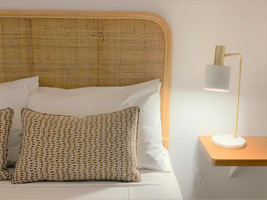 a bed with a wooden headboard next to a table with a lamp at Coast Yamba - Adults Only in Yamba