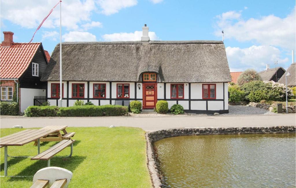 a building with a thatched roof next to a pond at Amazing Home In Sams With Wifi in Nordby