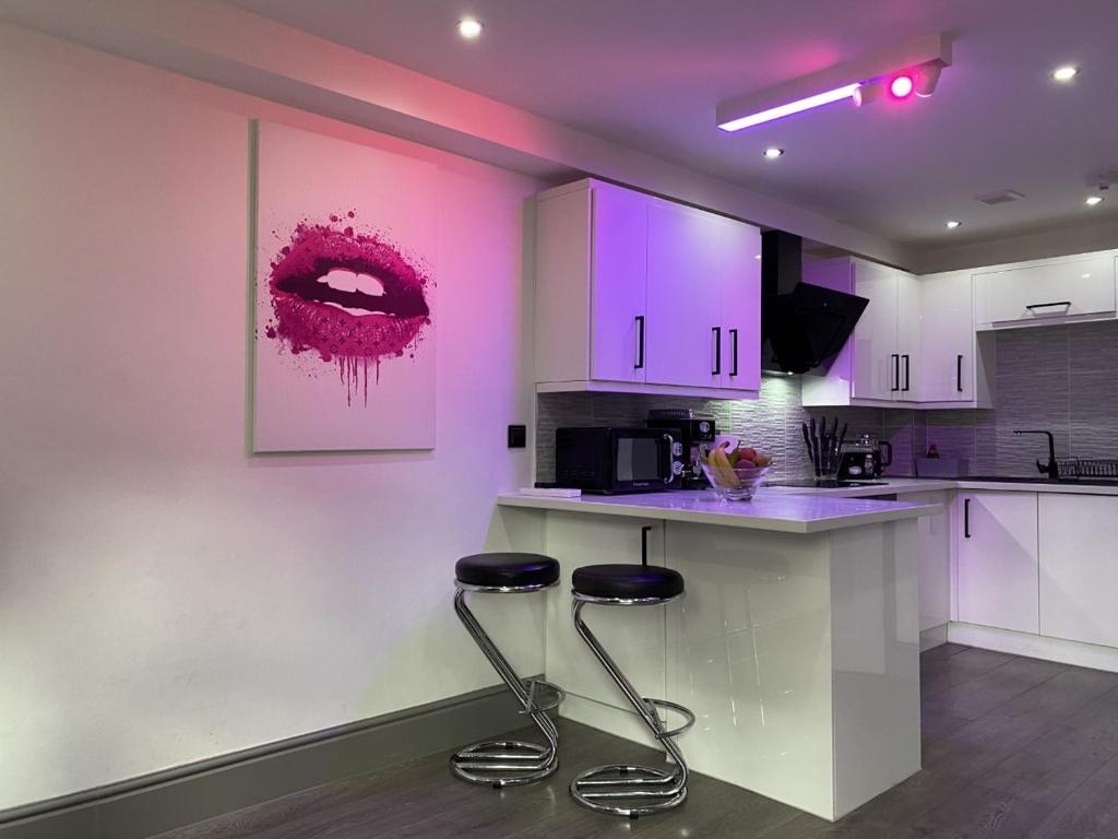a kitchen with two bar stools and purple cabinets at Modern Spacious 1 Bed Apartment with Free Parking in Trendy Inner London Suburb 15 mins walk to Victoria Line Underground then 20 mins to Oxford Street "West End of London" or 10 mins walk to Overground and 10 mins to London Liverpool St "City of London" in London