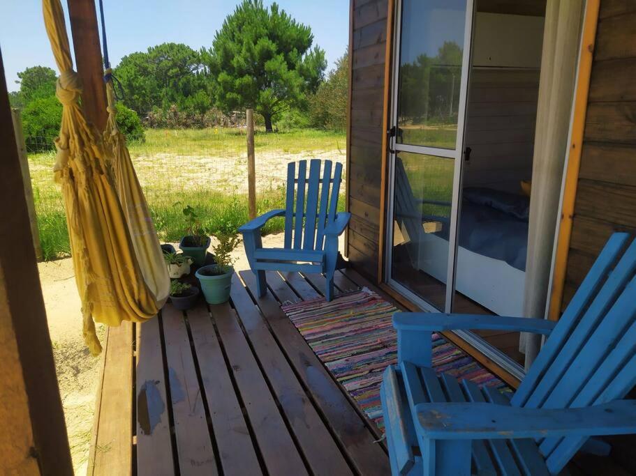 zwei blaue Stühle und ein Regenschirm auf einer Veranda in der Unterkunft Glass in Punta Del Diablo