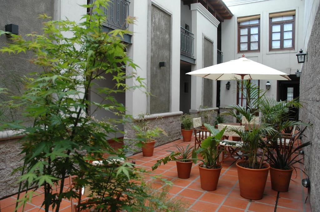 un patio con sombrilla, sillas y macetas en Posada Gotan en Buenos Aires