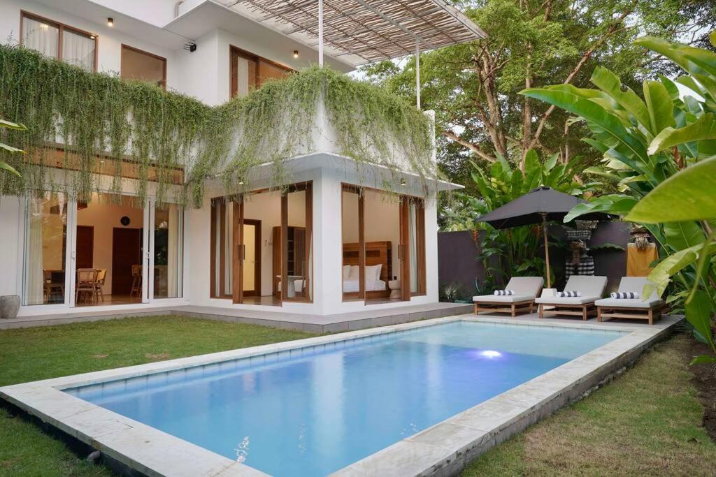 a villa with a swimming pool in front of a house at Villa Ikris - tranquil oasis in the heart of Canggu in Canggu