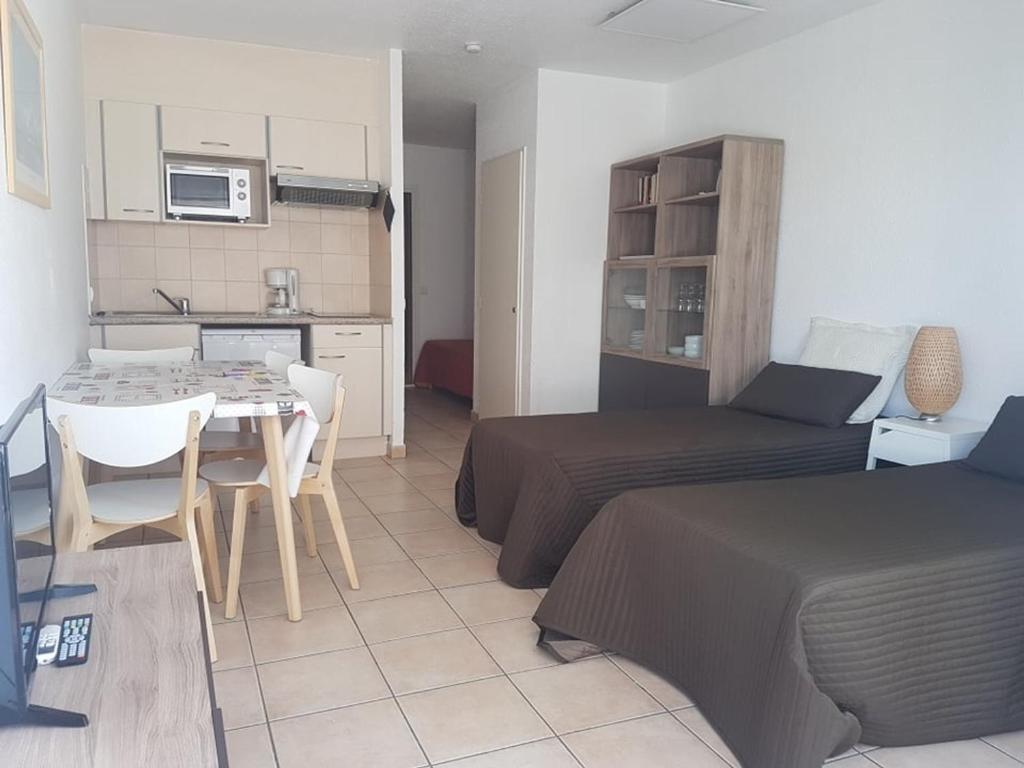 une chambre avec deux lits, une table et une cuisine dans l'établissement Studio climatisé proche plage et commerces avec WiFi - FR-1-466A-31, à Saint-Raphaël
