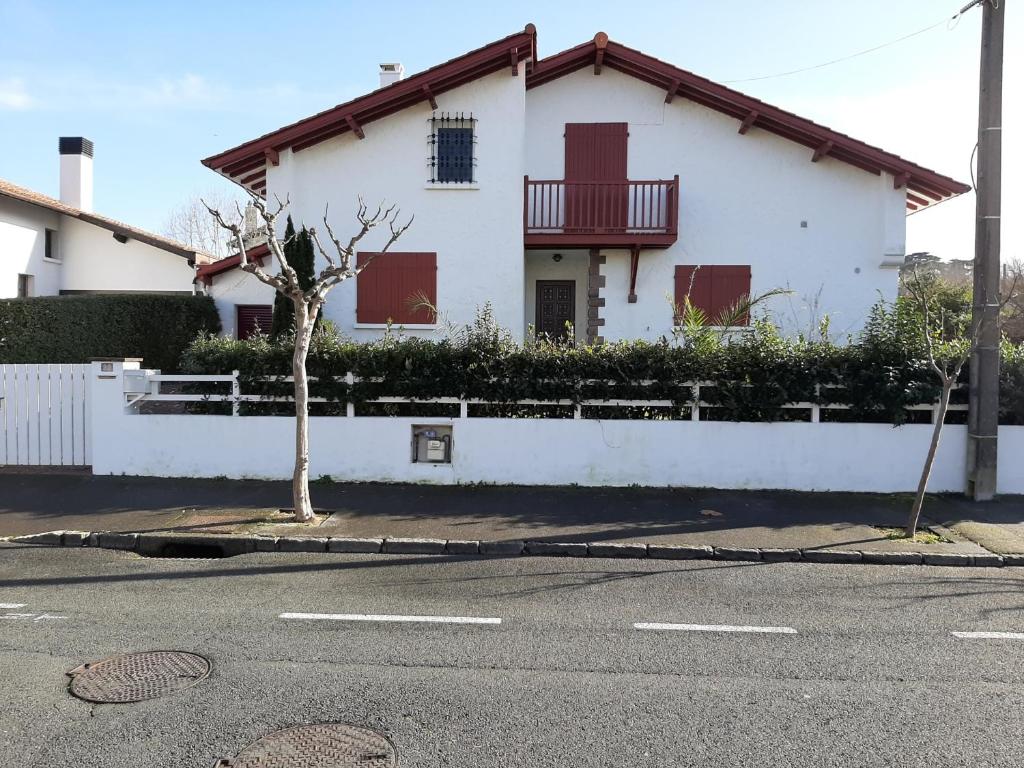 una casa blanca con persianas rojas en una calle en Maison Hendaye, 7 pièces, 12 personnes - FR-1-239-492, en Hendaya