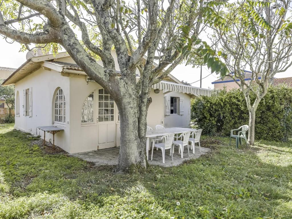 une maison blanche avec une table et des chaises sous un arbre dans l'établissement Maison de charme 3 ch. à 350m de la plage - jardin, BBQ, animaux admis, idéale pour 6 pers. - FR-1-521-111, à Biscarrosse-Plage