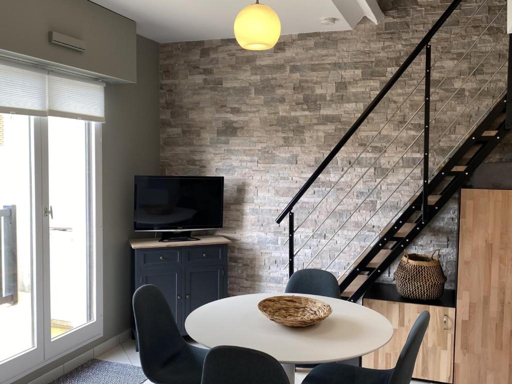 un salon avec une table et des chaises et un escalier dans l'établissement Cabourg: Appartement 3P à 200m de la plage, 2 chambres, balcon, internet - FR-1-487-277, à Cabourg