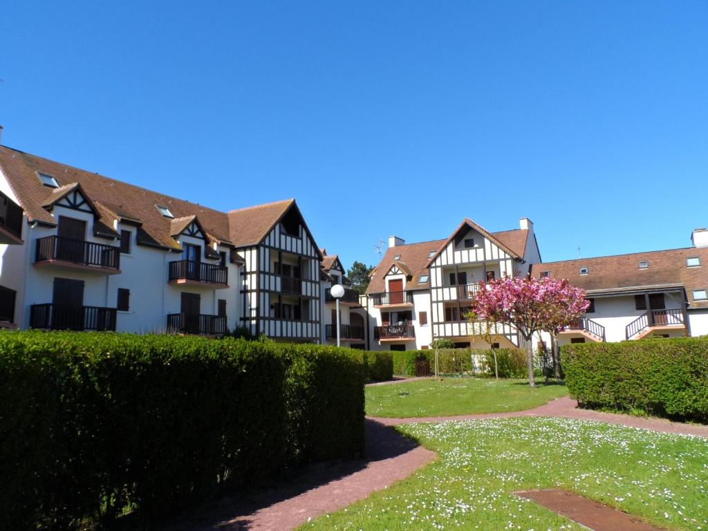a row of houses in a park with bushes at Duplex 3 Pièces Proche Plage à Cabourg, 6 Pers., Parking Privé - FR-1-487-280 in Varaville