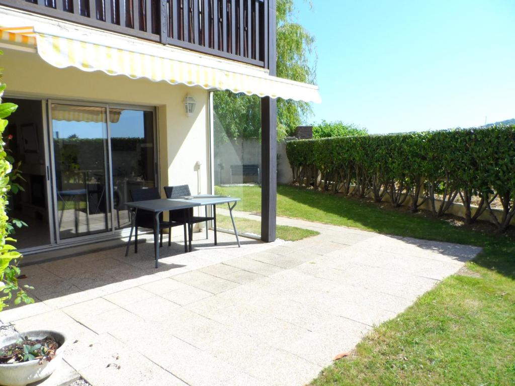 un patio avec une table et des chaises dans une cour dans l'établissement Appartement T2 avec Jardin, Proche Centre et Plage de Cabourg, Parking Inclus - FR-1-487-295, à Cabourg