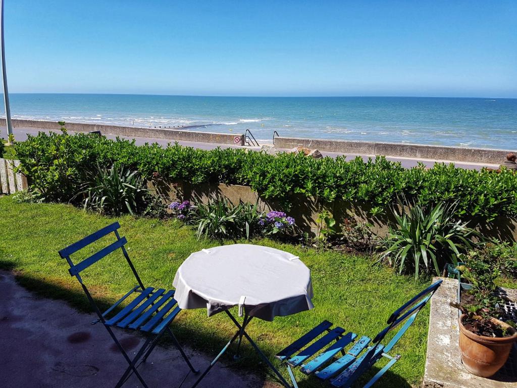 une table et des chaises avec l'océan en arrière-plan dans l'établissement Cabourg : Appartement moderne 4/5 pièces, accès plage, 8 pers, jardin et terrasse, parking, WIFI - FR-1-487-304, à Cabourg