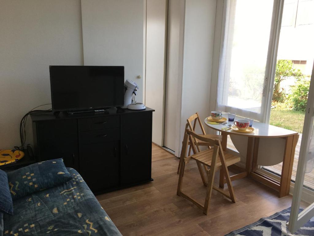 un salon avec une télévision et une table dans l'établissement Appartement 2 pièces avec terrasse près de la plage - Merville-Franceville - FR-1-487-311, à Merville-Franceville-Plage