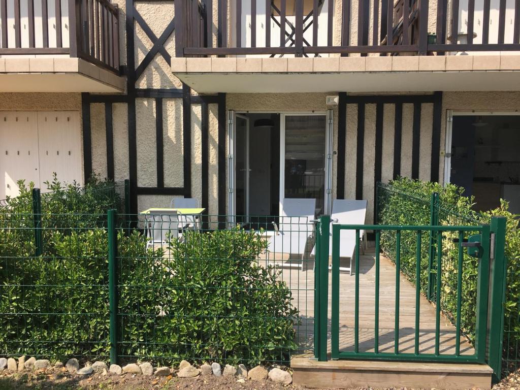 a green fence in front of a house at Studio Merville-Franceville-Plage, 1 pièce, 3 personnes - FR-1-487-222 in Merville-Franceville-Plage