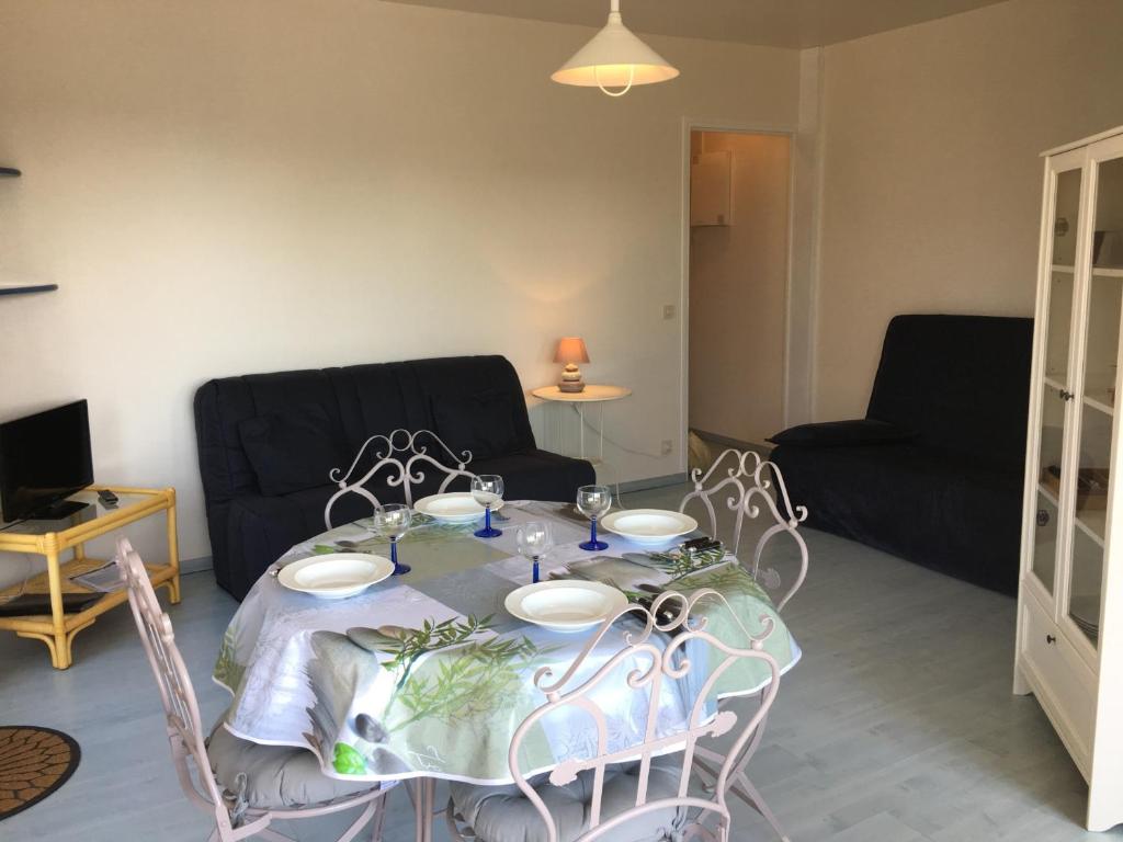 - une table à manger avec des chaises et un canapé dans l'établissement Grand studio en hyper-centre de Cabourg avec balcon, proche plage, parking, et prestations disponibles - FR-1-487-327, à Cabourg