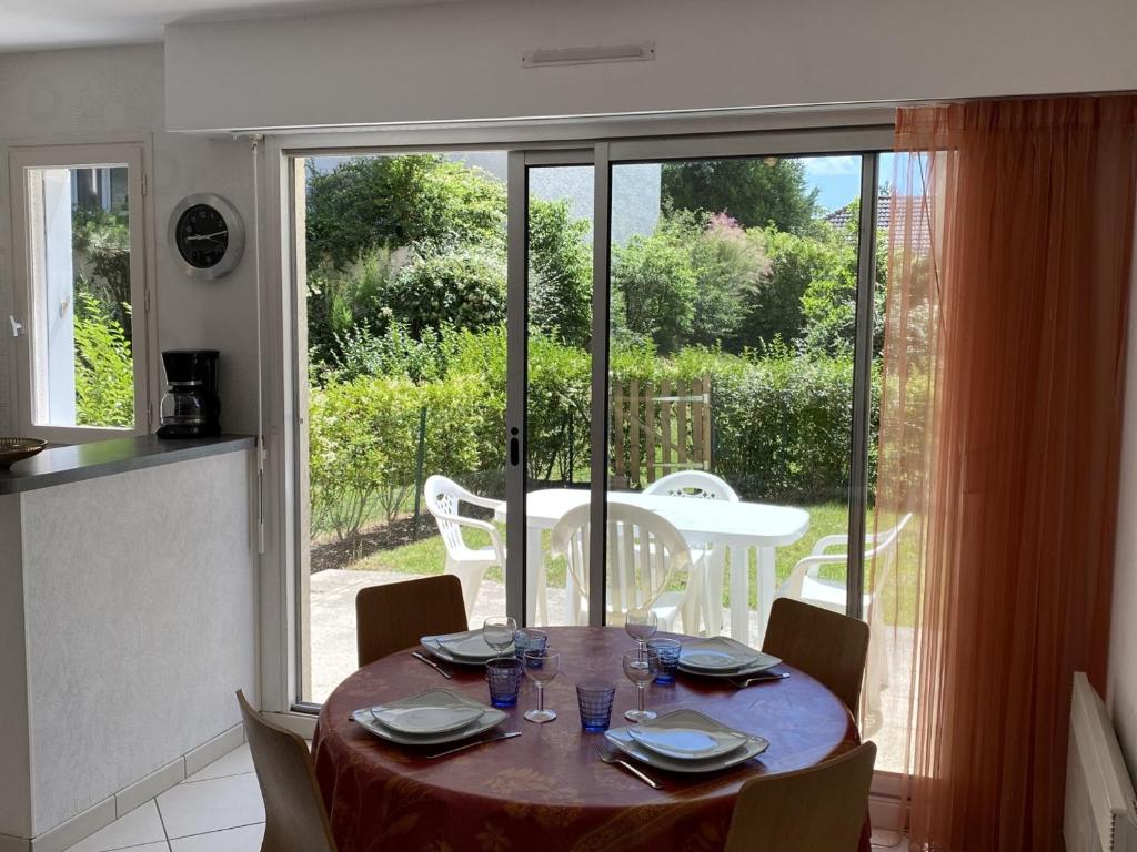 une table de salle à manger avec des chaises et une grande fenêtre dans l'établissement Cabourg : Studio Rez-de-Jardin Proche Plage, Animaux Acceptés, TV, Wi-Fi Optionnel - FR-1-487-331, à Cabourg